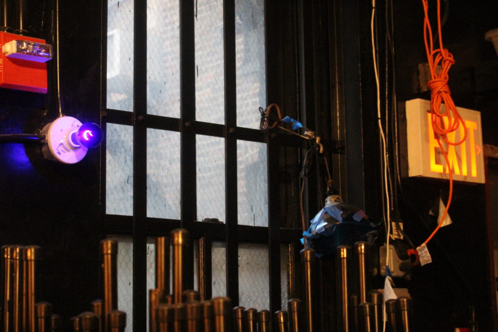 Une vitre et quelques équipements lumineux de théâtre : gaines, ampoules, interrupteur
